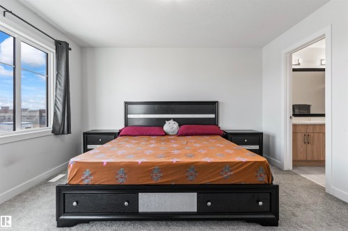 Spacious room featuring light gray carpeting, neutral wall paint, and a large window with dark trim - 8046 Kiriak Link, Edmonton, AB - Indoor Photo Showing Bedroom