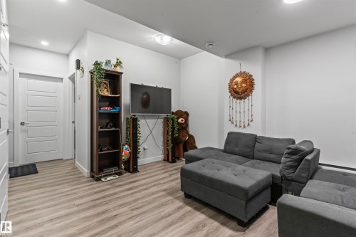 Contemporary living area featuring wood-finish flooring and recessed lighting - 8046 Kiriak Link, Edmonton, AB - Indoor
