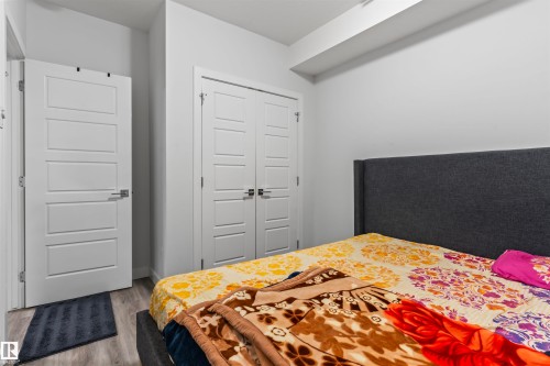 Room featuring a paneled interior door, a bi-fold closet door with horizontal paneling, and wood-finish flooring - 8046 Kiriak Link, Edmonton, AB - Indoor Photo Showing Bedroom