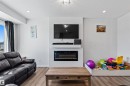 Integrated entertainment wall featuring a mounted media screen, a floating shelf, and a built-in electric fireplace - 8046 Kiriak Link, Edmonton, AB  - Indoor Photo Showing Living Room With Fireplace 