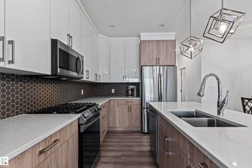 Modern kitchen featuring white upper cabinetry, wood-finish lower cabinetry, and light-toned countertops - 8046 Kiriak Link, Edmonton, AB - Indoor Photo Showing Kitchen With Double Sink With Upgraded Kitchen