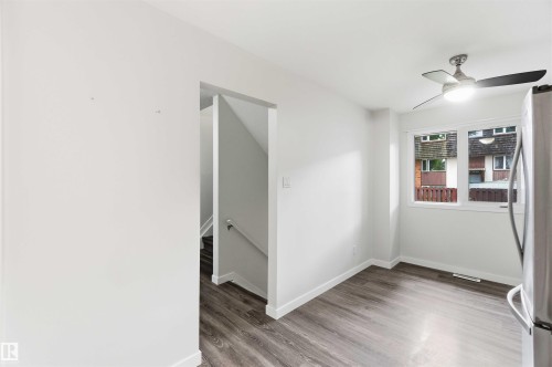 Bright interior space featuring wood-finish flooring, a contemporary ceiling fan, and a double window with white trim - 3312 106 Avenue, Edmonton, AB 