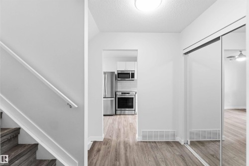 Wood-finish flooring throughout, complemented by a contemporary kitchen featuring stainless steel appliances - 3312 106 Avenue, Edmonton, AB 
