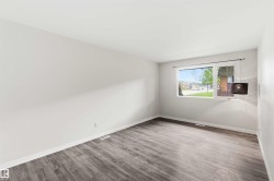 Bright interior space featuring a large window, light-toned walls, and wood-finish flooring - 