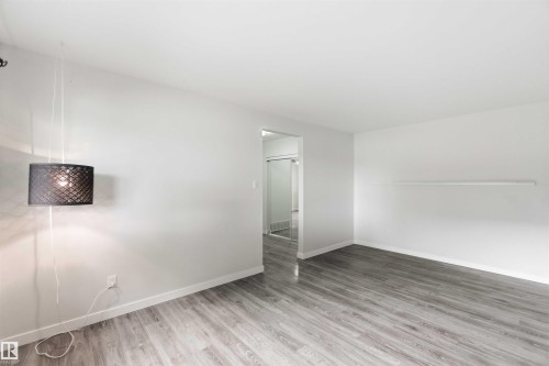 Spacious room featuring wood-finish flooring, light gray walls, and an open doorway - 3312 106 Avenue, Edmonton, AB 