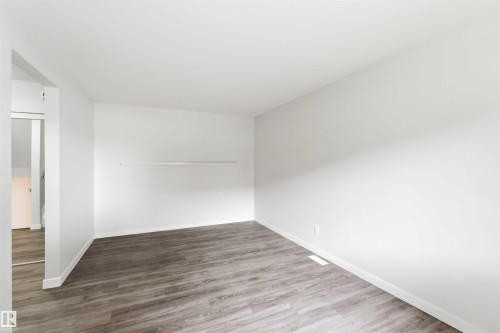 Spacious room featuring wood-finish flooring, white baseboards, and a neutral color palette - 3312 106 Avenue, Edmonton, AB 