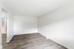 Spacious room featuring wood-finish flooring, white baseboards, and a neutral color palette - 