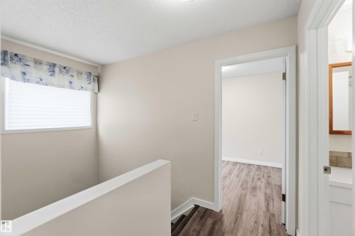 Upper-level landing featuring wood-finish flooring, a white window blind, and a neutral color palette - 3312 106 Avenue, Edmonton, AB 