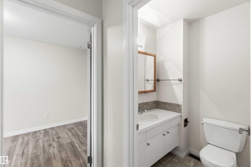 Bathroom with white vanity, integrated sink, and wood-framed medicine cabinet - 3312 106 Avenue, Edmonton, AB 