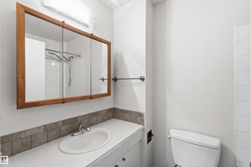 Bathroom featuring a built-in vanity with an oval sink and a chrome faucet, complemented by a tiled backsplash - 3312 106 Avenue, Edmonton, AB 
