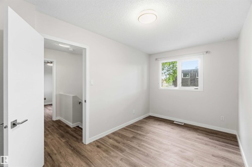 Bright room featuring wood-finish flooring, a contemporary ceiling light fixture, and a white framed window - 3312 106 Avenue, Edmonton, AB 