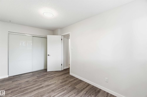 Room with wood-finish flooring, white walls, and a modern ceiling light fixture - 3312 106 Avenue, Edmonton, AB 