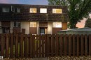 Two-story townhouse exterior featuring a wood-shingle roof, light-colored siding with brown accents, and white-framed windows - 3312 106 Avenue, Edmonton, AB 