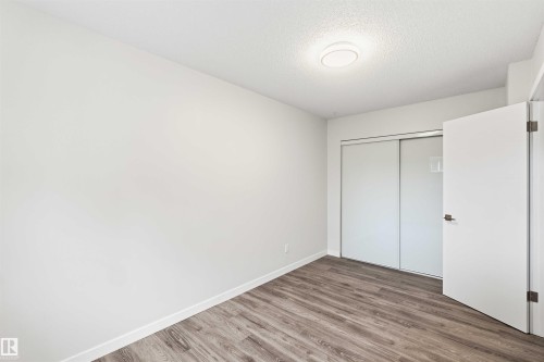Room featuring wood-finish flooring, white baseboards, and a flush-mount ceiling light - 3312 106 Avenue, Edmonton, AB 