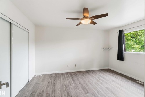 Bright room featuring wood-finish flooring and a ceiling fan with integrated lighting - 3312 106 Avenue, Edmonton, AB 
