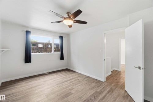 Bright interior space featuring wood-finish flooring, white walls, and a ceiling fan with integrated lighting - 3312 106 Avenue, Edmonton, AB 