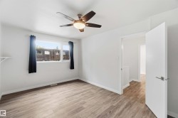 Bright interior space featuring wood-finish flooring, white walls, and a ceiling fan with integrated lighting - 