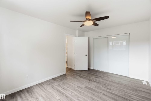 Room featuring wood-finish flooring, white baseboards, and a modern ceiling fan with integrated lighting - 3312 106 Avenue, Edmonton, AB 