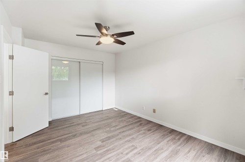 Room with wood-finish flooring, white walls, and a ceiling fan with integrated lighting - 3312 106 Avenue, Edmonton, AB 