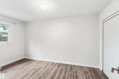 Room featuring wood-finish flooring, white baseboards, and neutral wall paint - 3312 106 Avenue, Edmonton, AB 