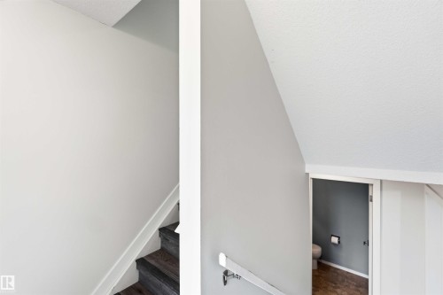 Interior staircase featuring wood-finish treads and a white handrail - 3312 106 Avenue, Edmonton, AB 