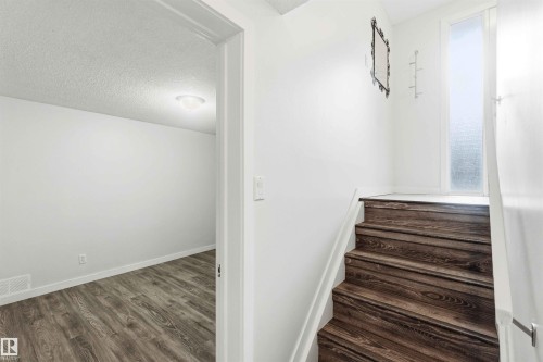 Entryway featuring wood-finish stairs with white risers and railing - 3312 106 Avenue, Edmonton, AB 