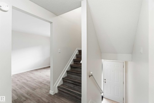 Interior staircase featuring wood-finish treads and risers with a white handrail - 3312 106 Avenue, Edmonton, AB 