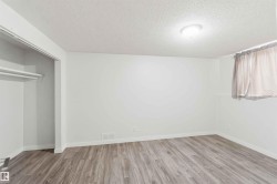 Spacious room featuring wood-finish flooring, white walls, and a recessed closet with shelving - 