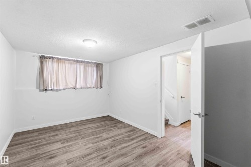 Bright room featuring wood-finish flooring, white walls, and a contemporary ceiling light fixture - 3312 106 Avenue, Edmonton, AB 