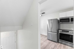 Contemporary kitchen featuring stainless steel appliances, white cabinetry, and a subway tile backsplash - 