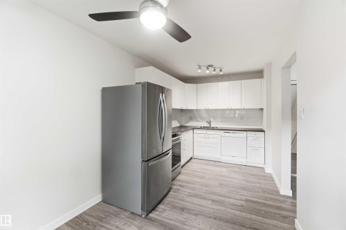 Kitchen featuring white cabinetry, wood-finish flooring, stainless steel appliances, a ceiling fan with light, and track lighting - 3312 106 Avenue, Edmonton, AB 