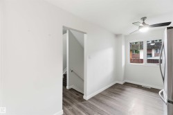 Bright interior space featuring wood-finish flooring, a contemporary ceiling fan, and a double window with white trim - 