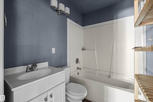 Bathroom featuring a white vanity with integrated sink, chrome faucet, and storage cabinetry - 7520 106 Street, Edmonton, AB 