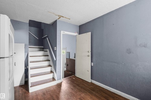 Wood-finish flooring throughout, complemented by a white-painted staircase with wood-finish treads - 7520 106 Street, Edmonton, AB 