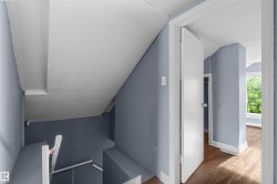 Sloped ceiling interior with light blue walls and wood-finish flooring - 