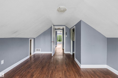 Room featuring sloped ceilings, wood-finish flooring, and white trim - 7520 106 Street, Edmonton, AB 