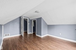 Room featuring wood-finish flooring, sloped ceilings, and light blue walls - 
