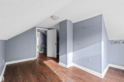 Attic space featuring sloped ceilings, wood-finish flooring, and light blue wall tones - 7520 106 Street, Edmonton, AB 
