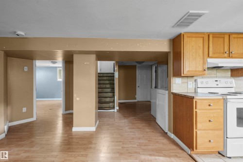 Kitchenette featuring wood cabinetry, laminate countertops, and a tile backsplash - 7520 106 Street, Edmonton, AB 