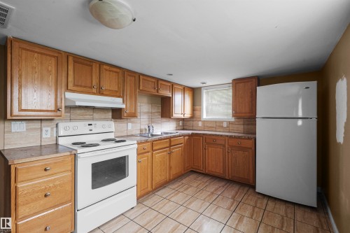 Kitchen featuring wood cabinetry, a tile backsplash, and a ceramic tile floor - 7520 106 Street, Edmonton, AB 