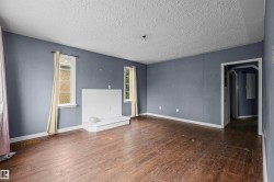 Spacious room featuring wood-finish flooring, light blue walls, and a textured white ceiling - 
