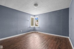 Room featuring wood-finish flooring, white baseboards, and a corner window with white trim - 