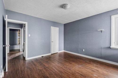 Room featuring wood-finish flooring, light blue wall paint, white trim, and a white ceiling - 7520 106 Street, Edmonton, AB 