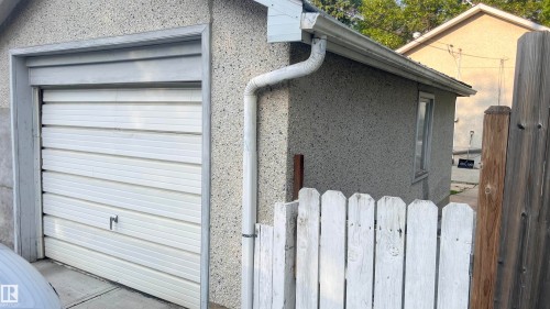 Detached garage featuring a white paneled door, stucco exterior, and a side window - 11404 92 Street Nw, Edmonton, AB - Outdoor With Exterior