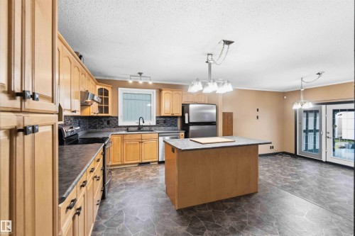 Kitchen featuring light wood cabinetry, dark countertops, and a full suite of stainless steel appliances - 17303 107 Street, Edmonton, AB 