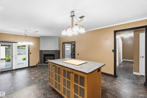 Kitchen island with wood-finish cabinetry, a gray countertop, and overhead lighting - 17303 107 Street, Edmonton, AB 