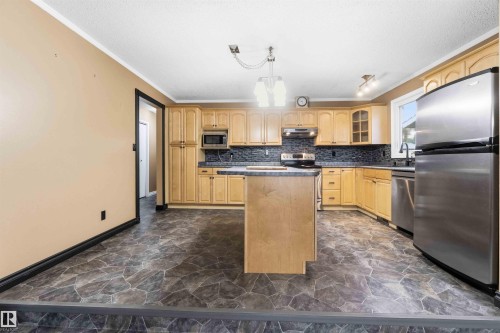 Kitchen featuring wood-finish cabinetry, dark countertops, and a full suite of stainless steel appliances - 17303 107 Street, Edmonton, AB 