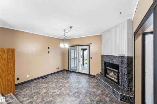 Living area featuring a corner fireplace with black tile surround, a gas insert, and a white wood-paneled accent wall - 17303 107 Street, Edmonton, AB 