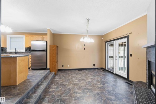 Open-concept area featuring a fireplace with stacked stone surround, dual pane French doors, and a multi-level floor plan - 17303 107 Street, Edmonton, AB 