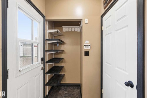 Entryway featuring a white paneled door with window, stone-look flooring, and a built-in storage system with multiple shelves and coat hooks - 17303 107 Street, Edmonton, AB 